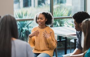 Upset teenage girl talks about emotions during therapy session During a group therapy session for teenagers, a teenage girl discusses her emotions.